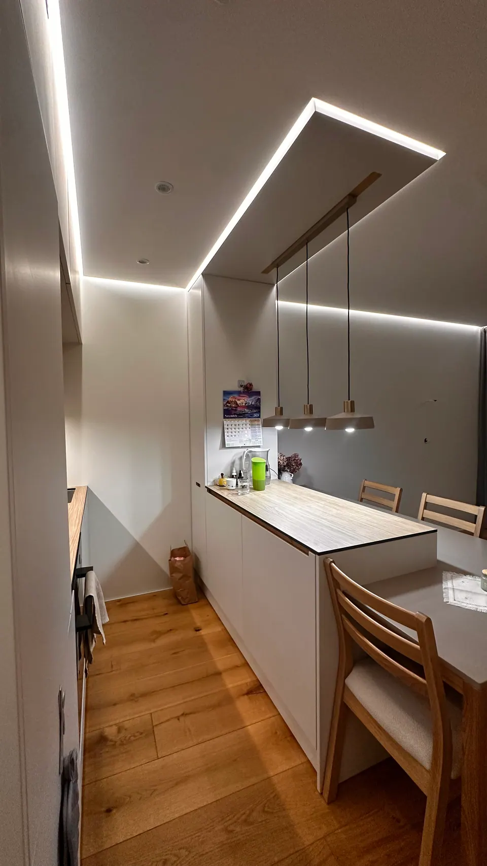 Kitchen in a Tallinn apartment with a floating ceiling and lit ceiling reveals, seen in perspective